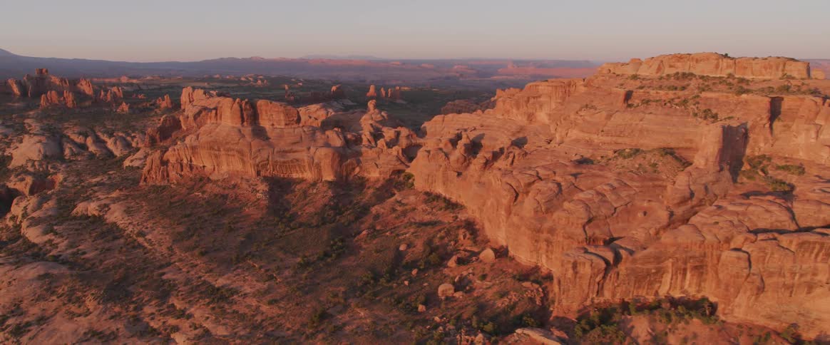 Badlands separated by valleys with mountains on the horizon