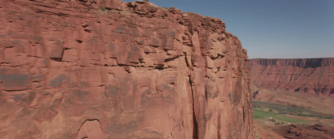 A red rocky plateau looms over a river flowing through a canyon