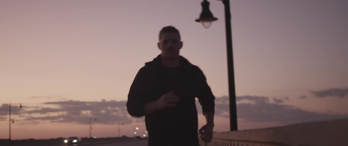 A man in a sweatshirt running down a sidewalk