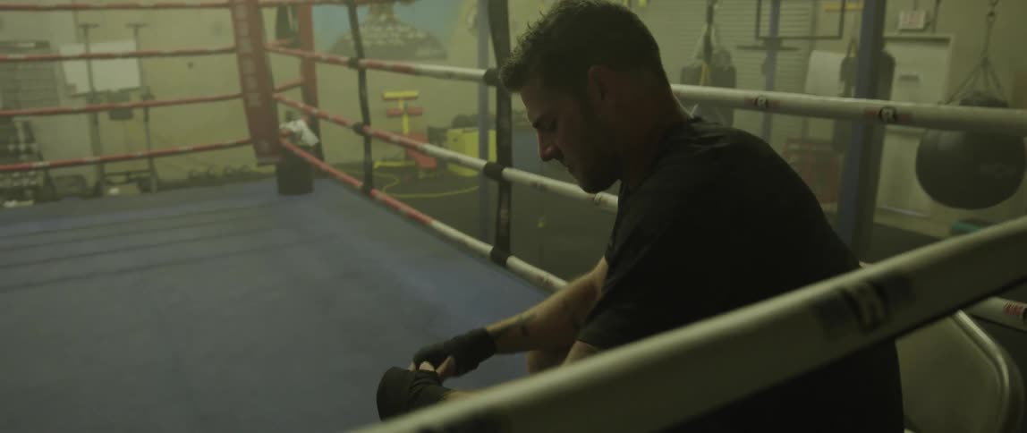 A boxer sits back against the ropes of a ring