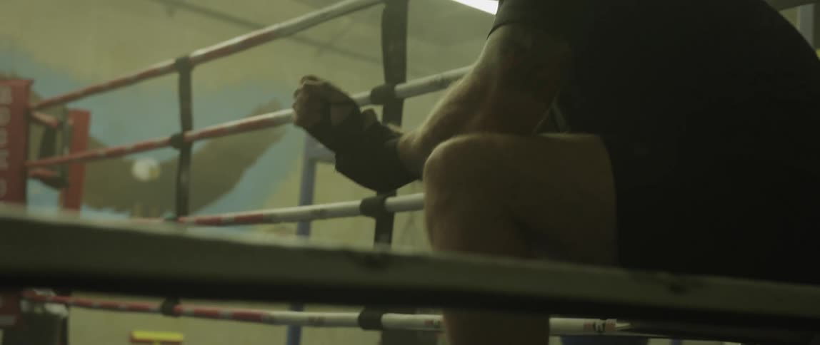 A man sitting in the corner of a boxing ring