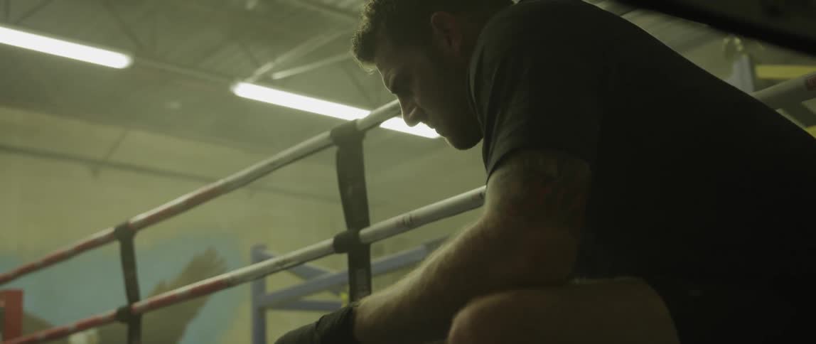 A man sits in the corner of a boxing ring
