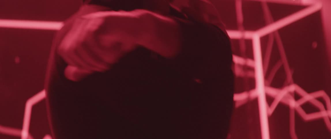 A man wearing a hoodie stretching inside a club with techno lights