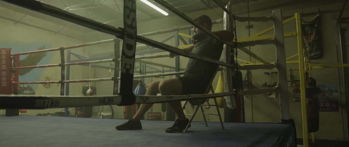 A man sits down in the corner of the boxing ring