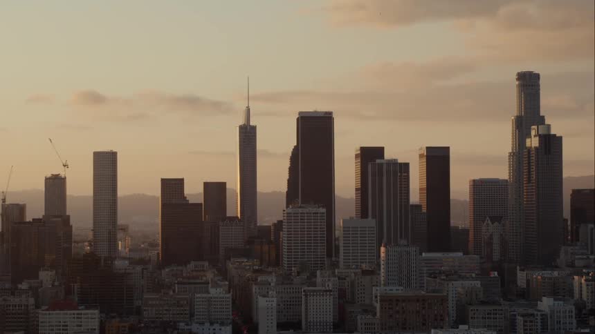Clouds float above city buildings and skyscrapers at sunset