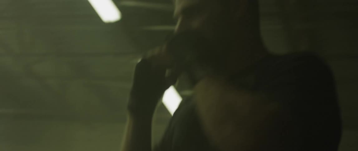 Man practices boxing by himself in dimly lit boxing ring