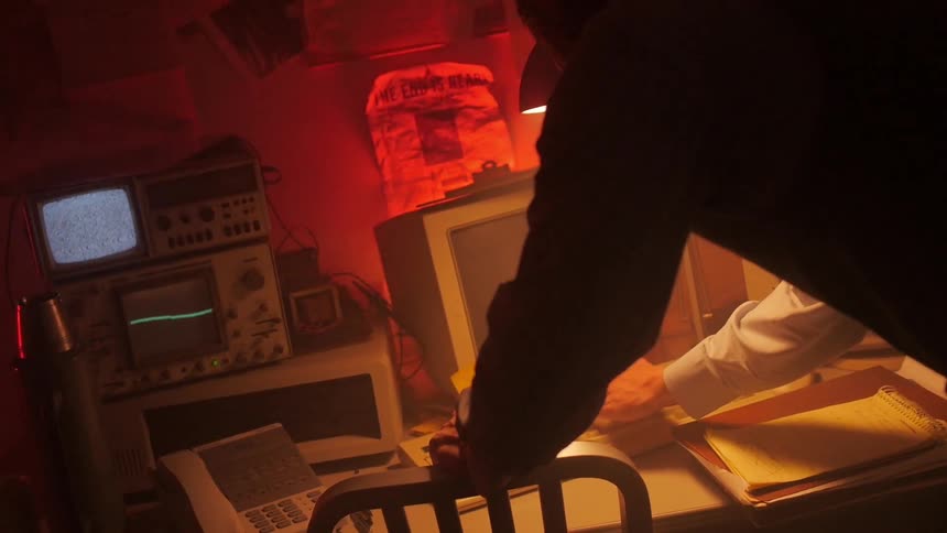 A standing person types on computer while nearby equipment flashes