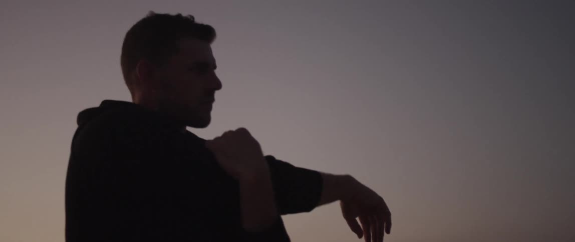 A man is walking and stretching outdoors