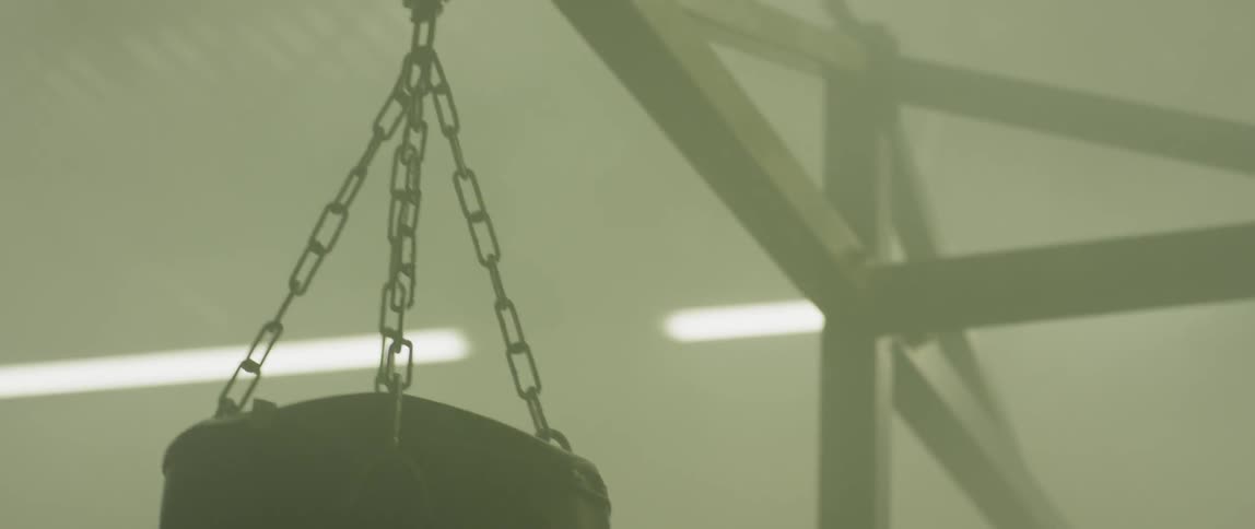 A heavy bag is hanging in the foggy gym