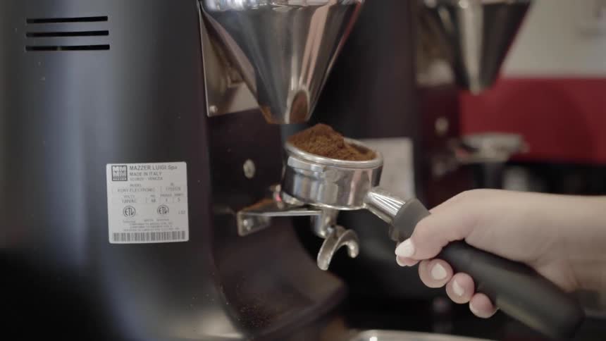 A person grinding coffee beans in an espresso machine