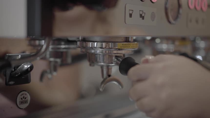 A woman attaches a coffee machine attachment to a machine