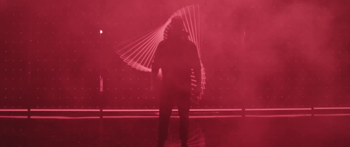 It's a man he is standing on the stage there is smoke and moving graphics in the background its red