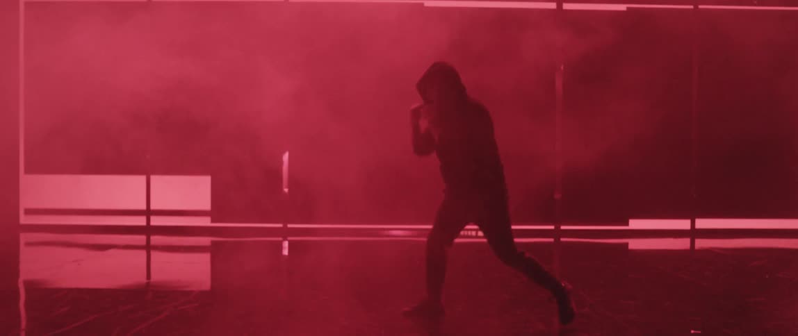A man shadow boxing on a stage in front of strobe lights
