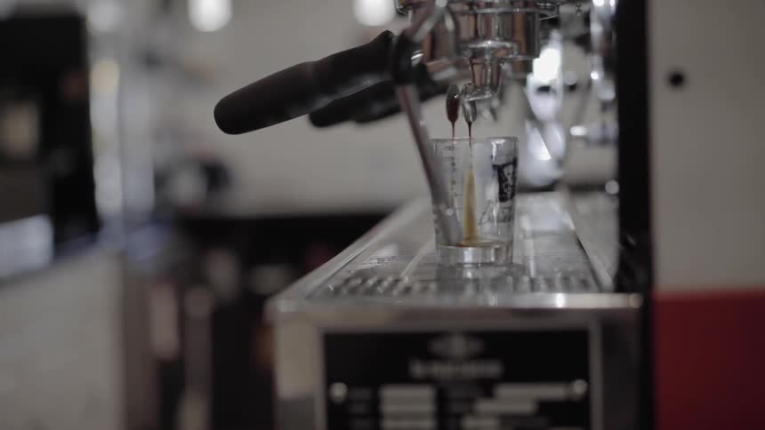 Coffee is dripping from a press into a glass cup