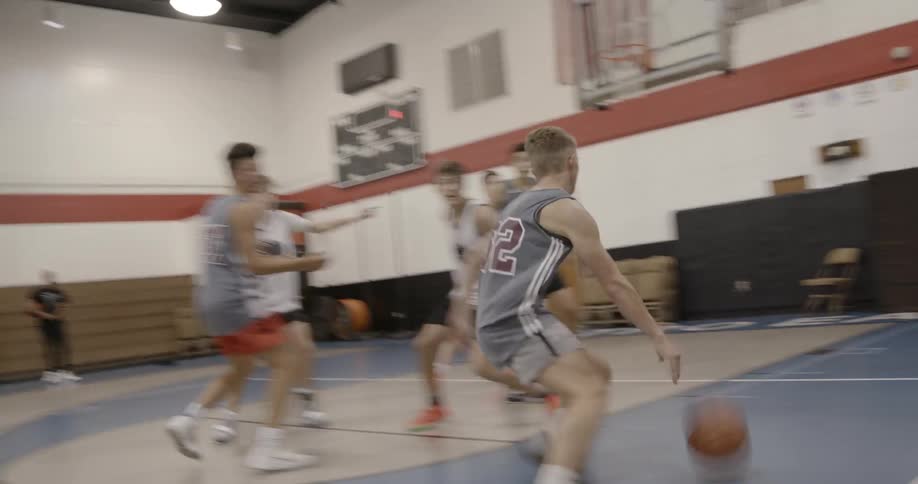 Two teams in an indoor gym playing basketball