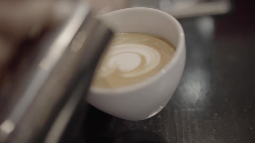 Person pouring milk into coffee to make a cappuccino