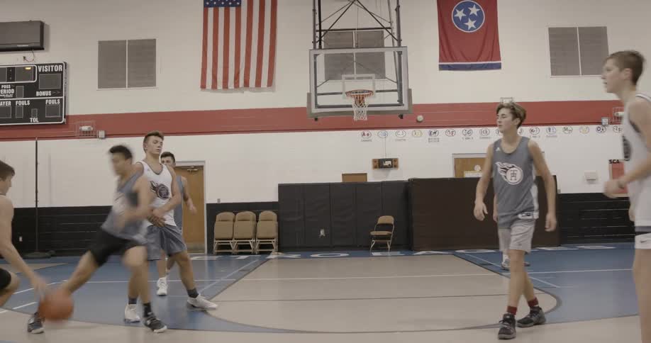 A male basketball player runs to the next and makes a lay up