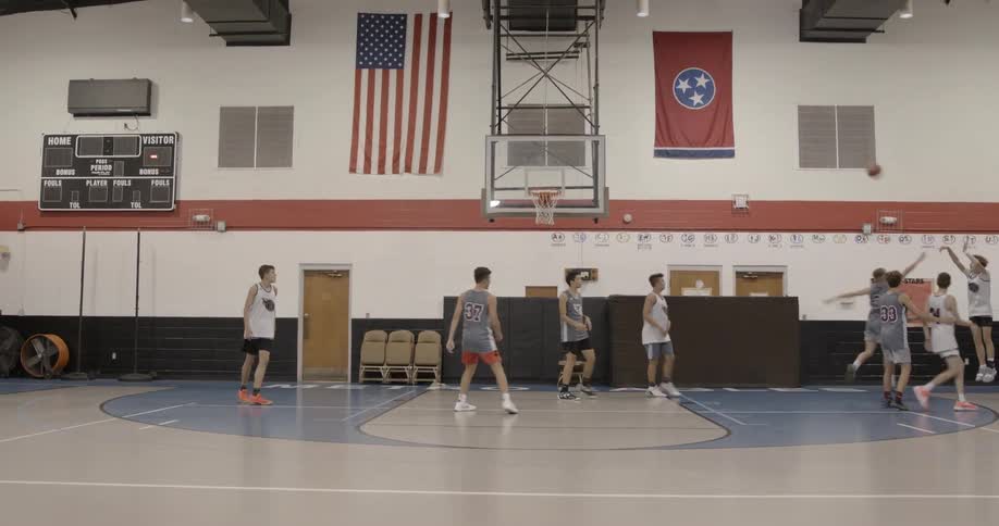 A group of teenage boys play basketball together