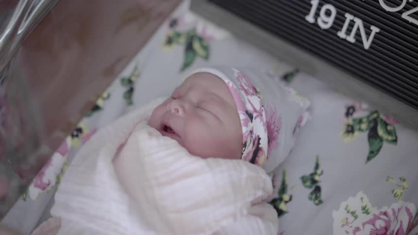 Woman touches newborn infant in the cradle during the daytime