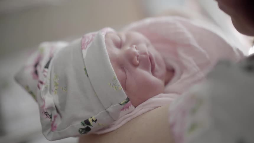 A baby yawns in the arms of its mother