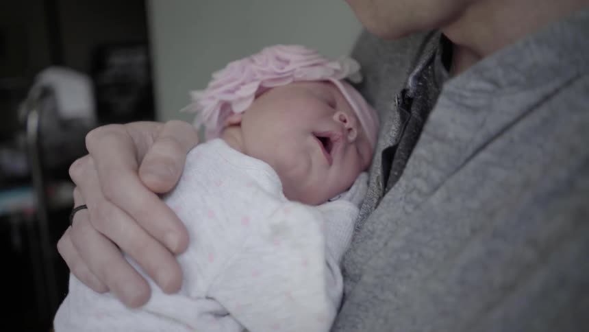 A white man holds a sleeping infant