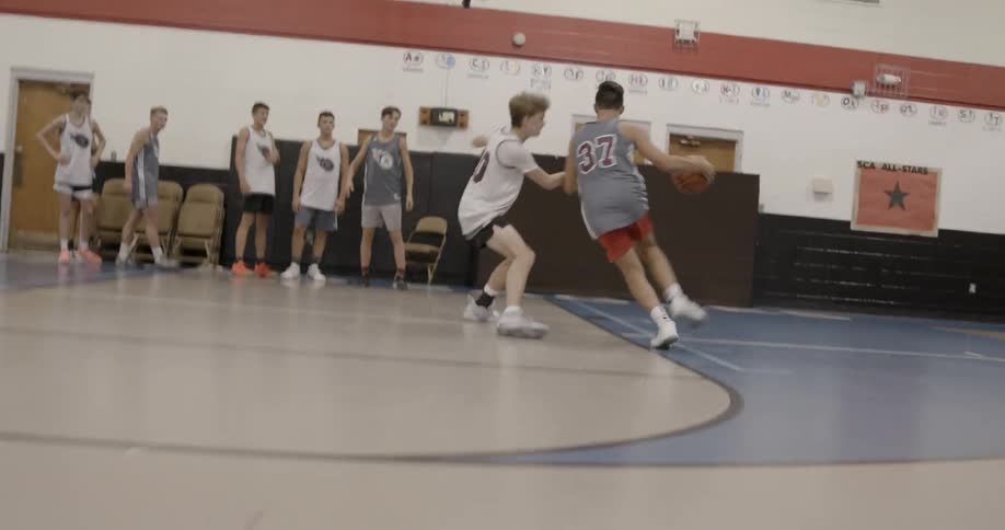 A person grabs a basketball and runs forward to shoot it