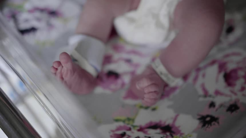 A newborn baby in a hospital crib