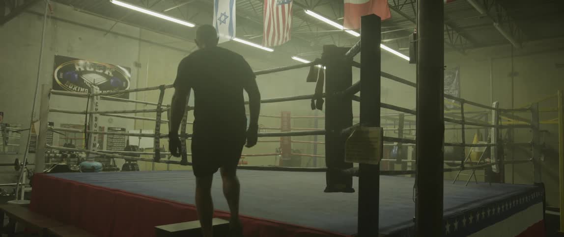Man climbing a boxing ring on gym