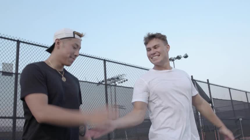 Two men smiling giving each other five on a tennis court