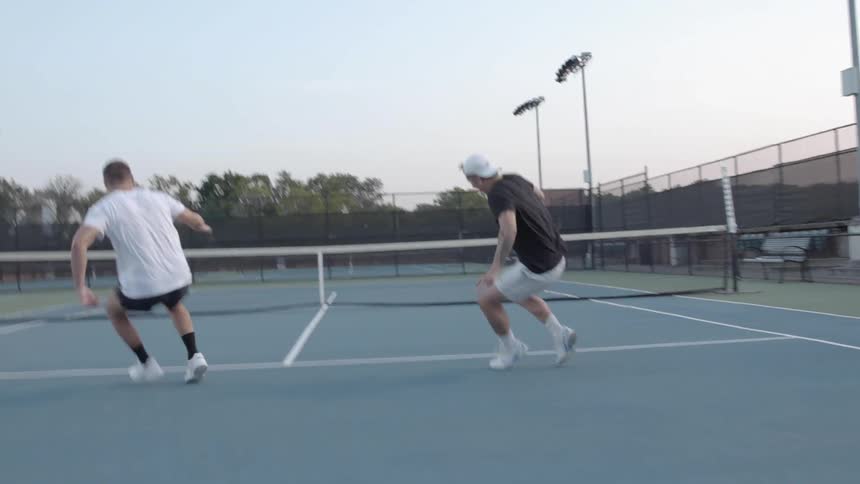 Two men race to the white line on a tennis court and turn around to run back to where they started from