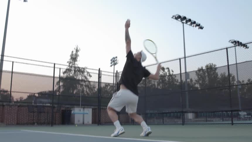 A young man serves a tennis ball
