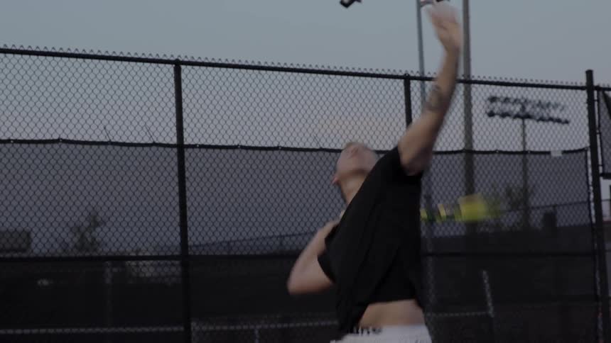 A man throws a tennis ball and hits it with a racket