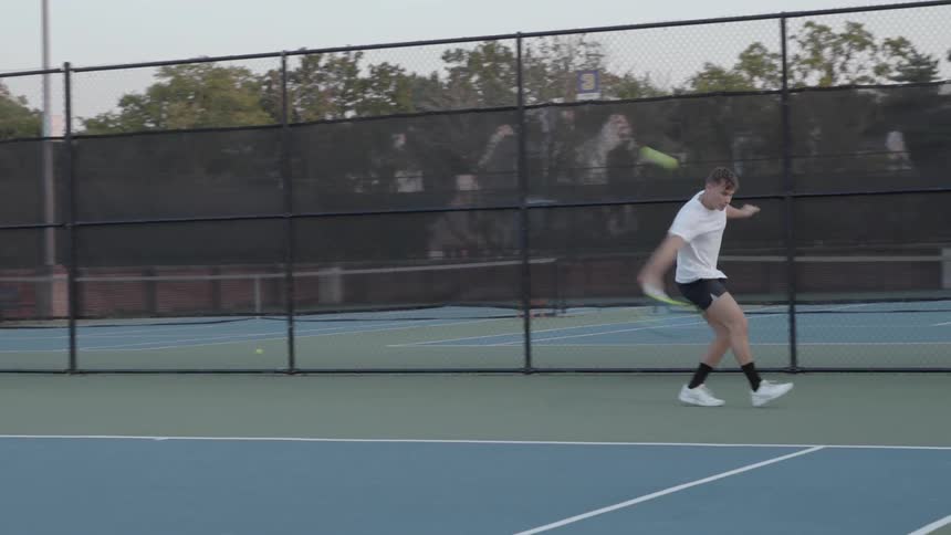 A tennis player returns a ball with his racquet