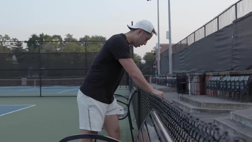A man is stretching on the tennis court