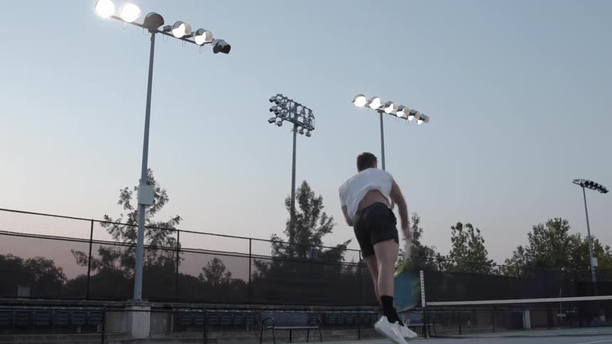 A man serves a tennis ball on a court