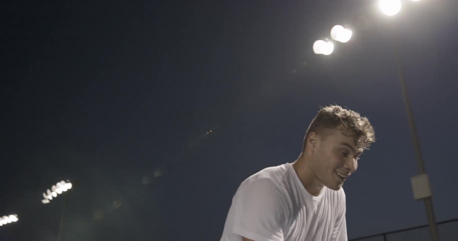 Tennis player touches tennis racket in the tennis court at dusk