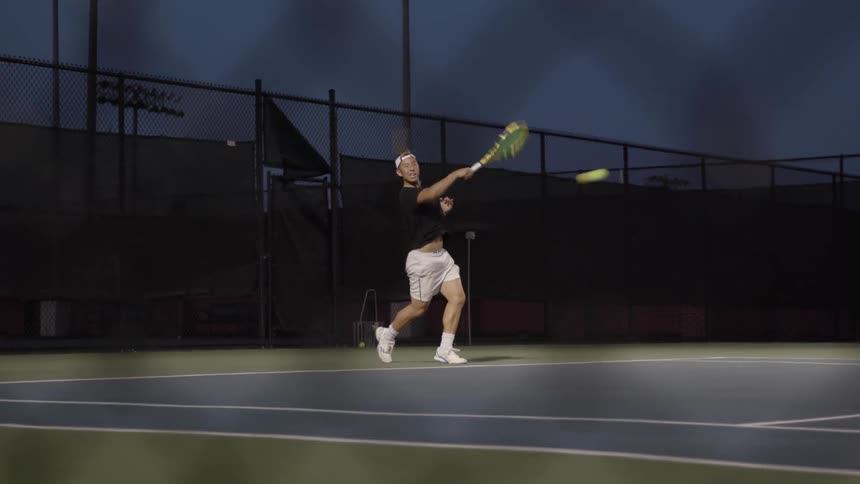 A young white man returns the ball on a tennis court