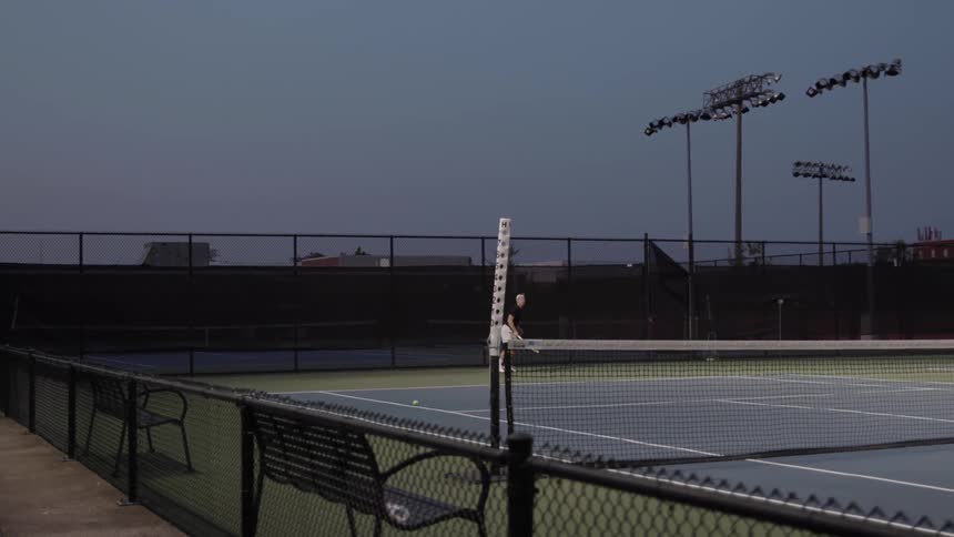 A man serves a tennis ball in a tennis court