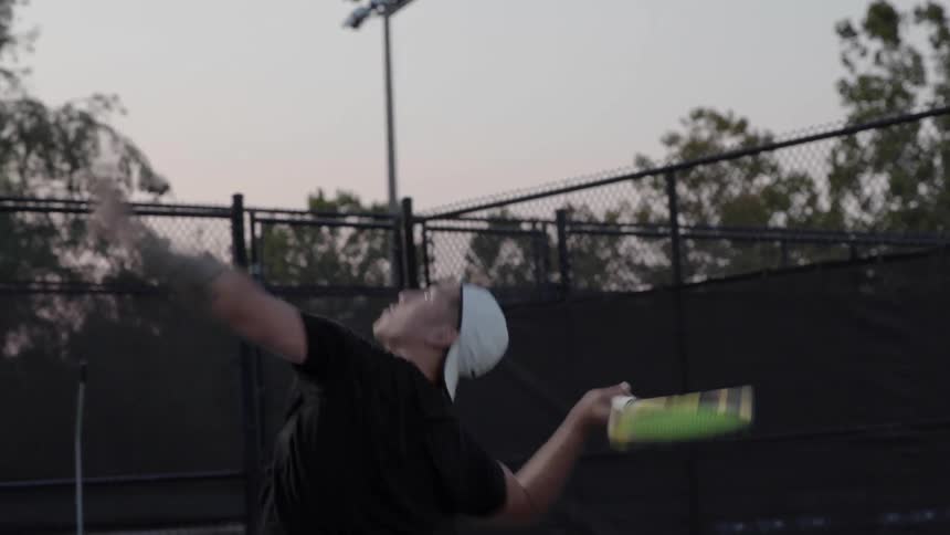 Man sets and serves tennis ball on court outdoors