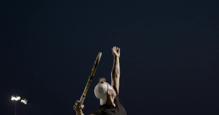 A man throws a tennis ball in the air and hits it