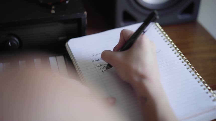 A woman writing on a notepad next to a piano