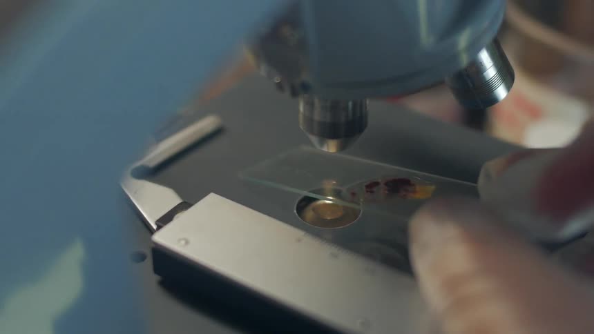 A man examines some blood under a telescope