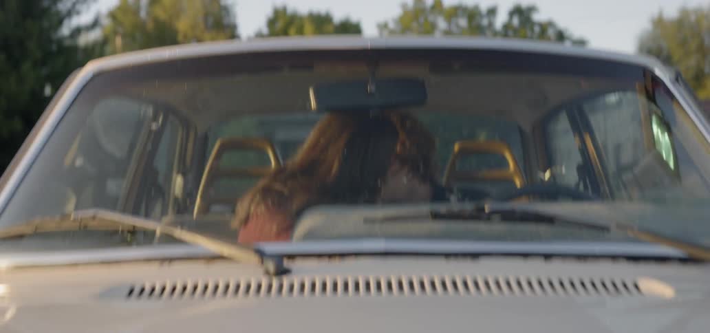 A young couple kiss in their car