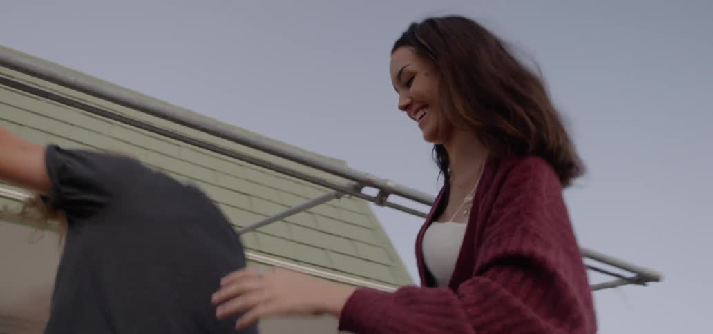 A couple plays around the outside of a house