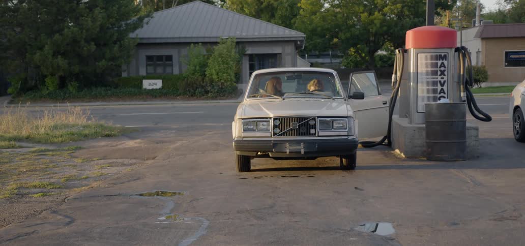 A young man gets into a car that is parked next to a vacuum cleaner