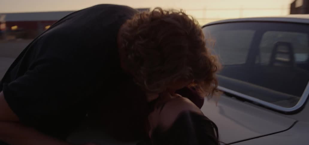 A man and woman kissing on top of a car