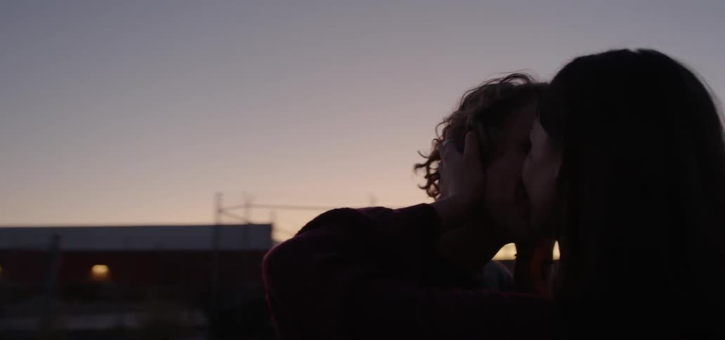 A man and women kiss outside at dusk