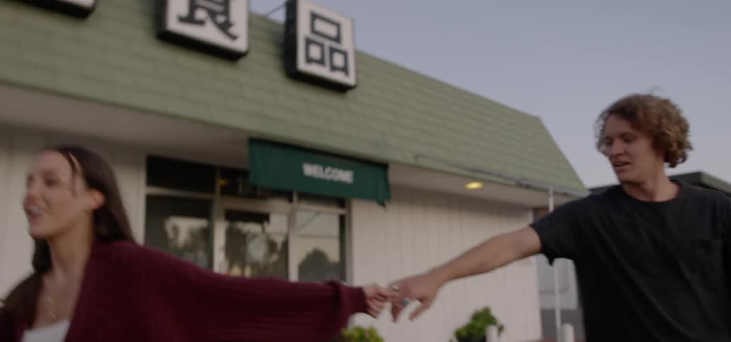 A man and woman playfully walk holding hands