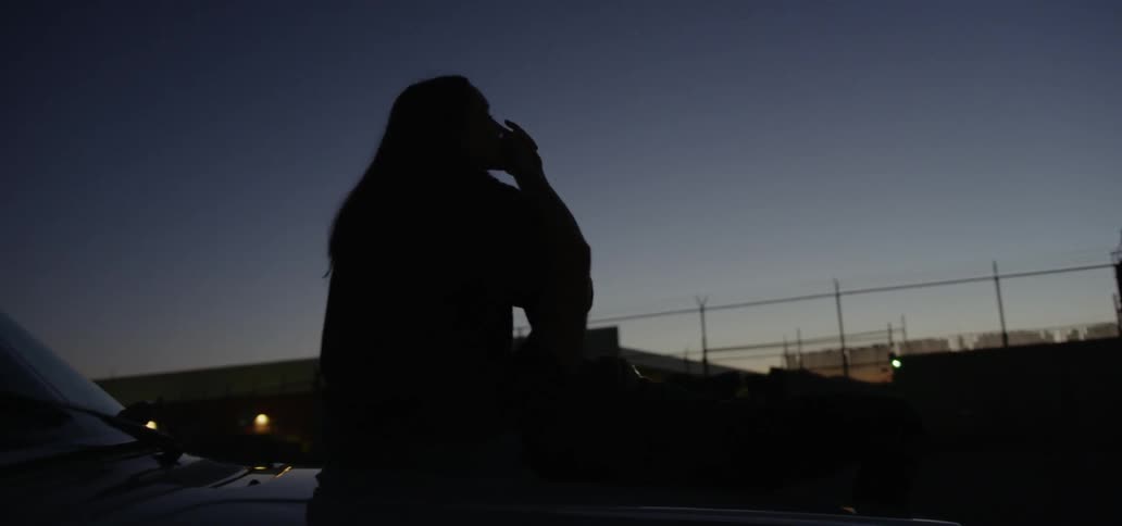 People hold hands on car hood at night