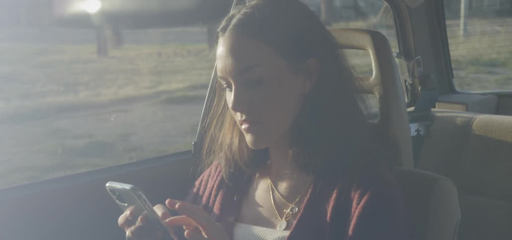 A woman sitting in a car touching her smartphone